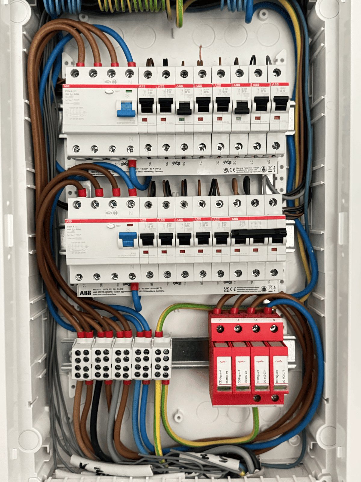 Tableau électrique neuf : disjoncteurs alignés, fils peignés, parafoudres rouges en bas